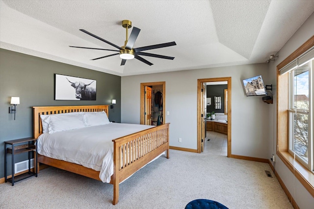 bedroom featuring a textured ceiling, carpet flooring, visible vents, baseboards, and a tray ceiling