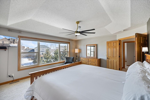 carpeted bedroom featuring a textured ceiling, a raised ceiling, visible vents, and a ceiling fan