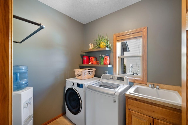 laundry area with cabinet space, a sink, washer and clothes dryer, and a textured ceiling