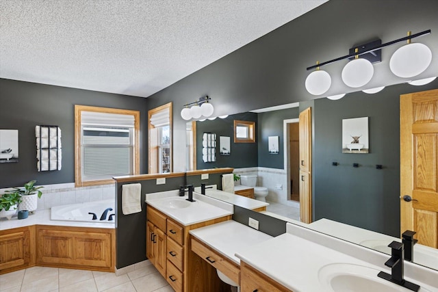 bathroom featuring a garden tub, tile patterned flooring, a textured ceiling, and vanity