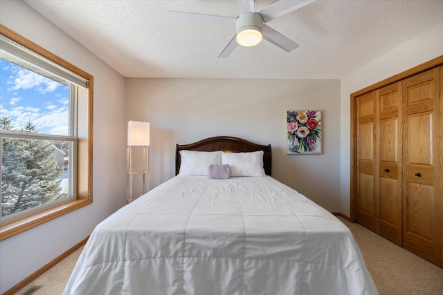 bedroom featuring a closet, light colored carpet, a textured ceiling, and baseboards