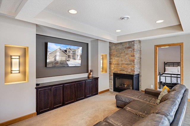 living area with a tray ceiling, light colored carpet, and a fireplace