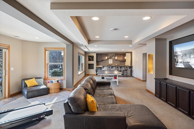 living area featuring recessed lighting, a raised ceiling, light colored carpet, and baseboards