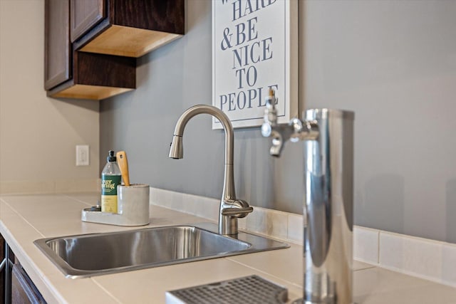 interior details with light countertops, dark brown cabinets, indoor bar, and a sink