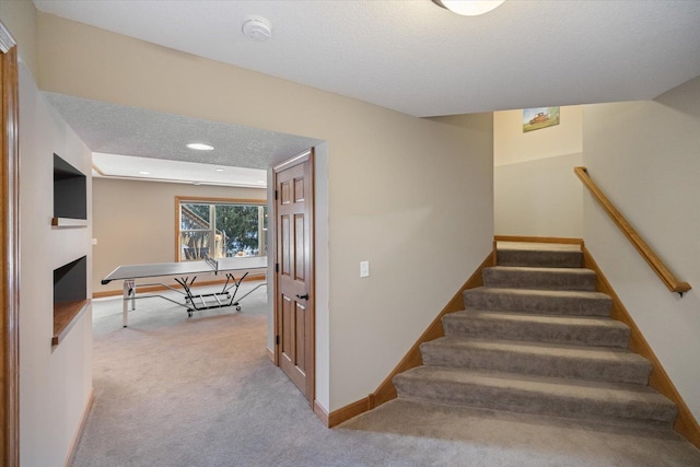 stairway with baseboards, a textured ceiling, carpet flooring, a fireplace, and recessed lighting