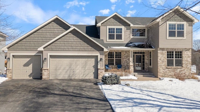 craftsman-style home featuring an attached garage, a porch, aphalt driveway, and brick siding