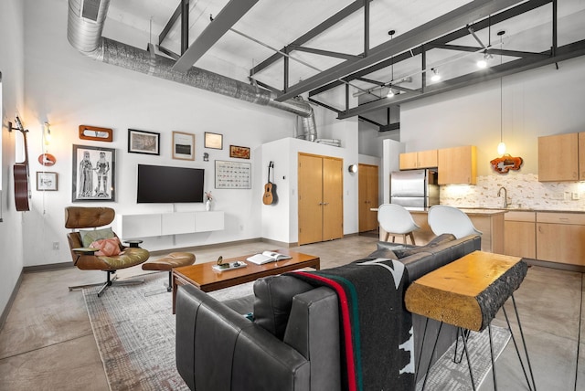 living room with a towering ceiling, concrete floors, and baseboards