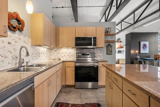 kitchen with light brown cabinetry, sink, light stone countertops, and appliances with stainless steel finishes