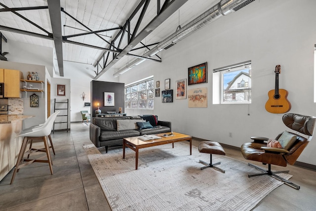 living area with concrete floors, a towering ceiling, and baseboards