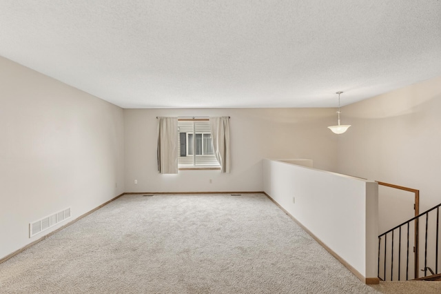 carpeted empty room featuring a textured ceiling