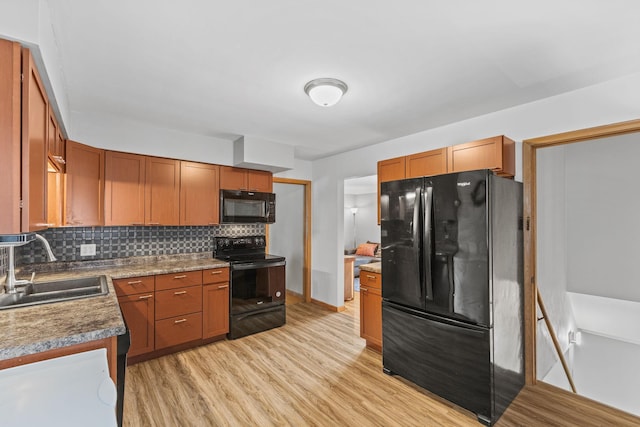 kitchen featuring decorative backsplash, sink, black appliances, and light hardwood / wood-style floors