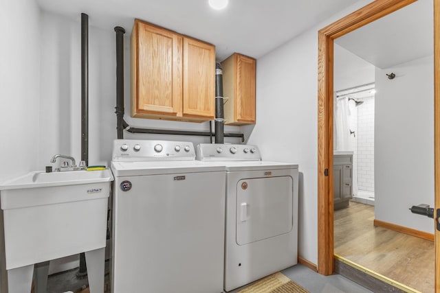 laundry area with cabinets, sink, washing machine and dryer, and light wood-type flooring