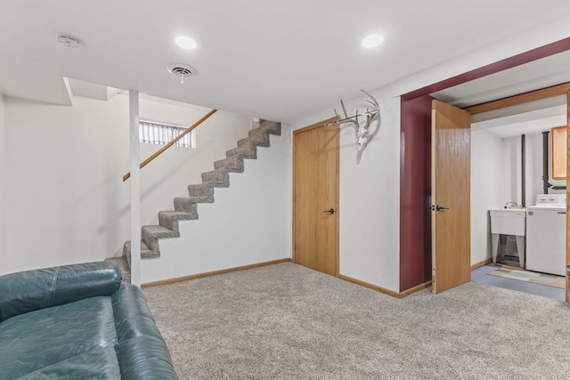 basement with light colored carpet, sink, and washer / dryer