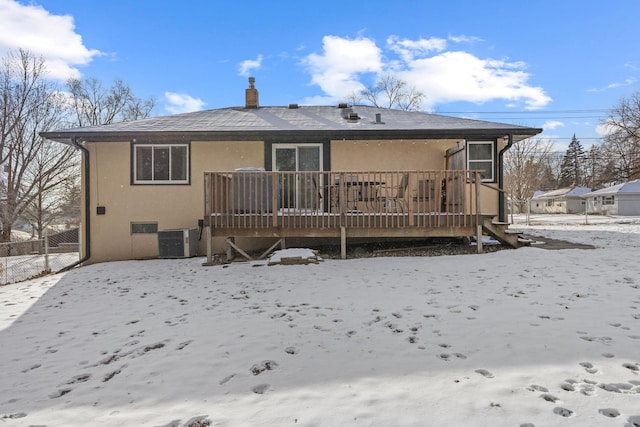 snow covered property with central AC unit and a deck