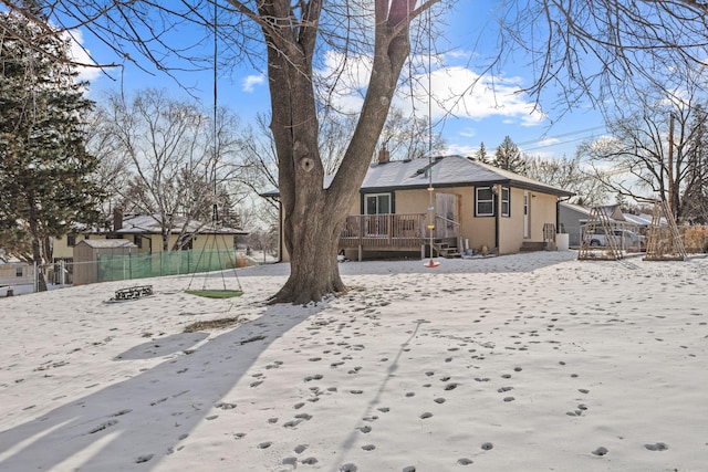 snow covered back of property with a deck