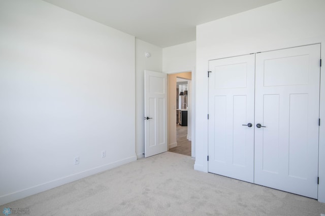 unfurnished bedroom featuring light carpet and a closet