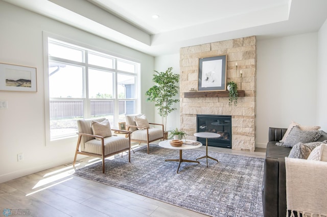 living area featuring hardwood / wood-style flooring, a tray ceiling, and a fireplace