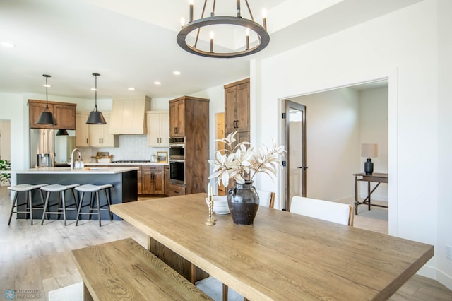 dining room featuring sink, a notable chandelier, and light wood-type flooring