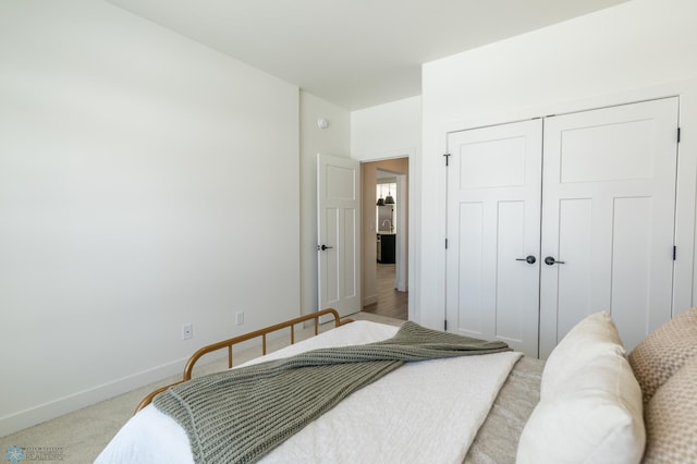 bedroom featuring a closet, light colored carpet, and baseboards