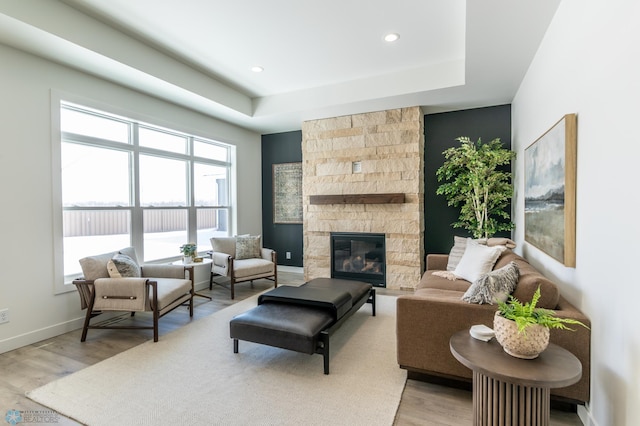 living area featuring light wood-style floors, recessed lighting, a stone fireplace, and baseboards