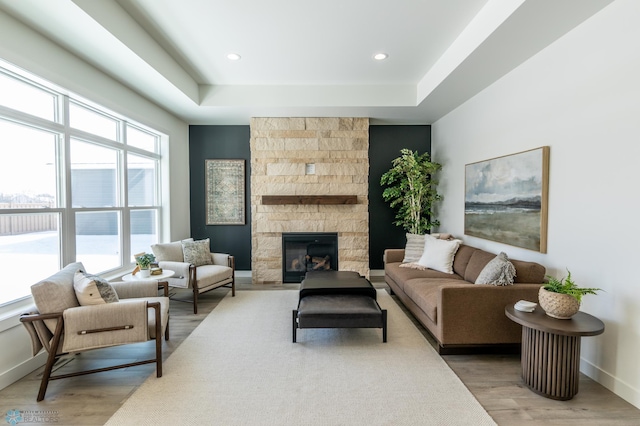 living area featuring recessed lighting, baseboards, wood finished floors, and a stone fireplace