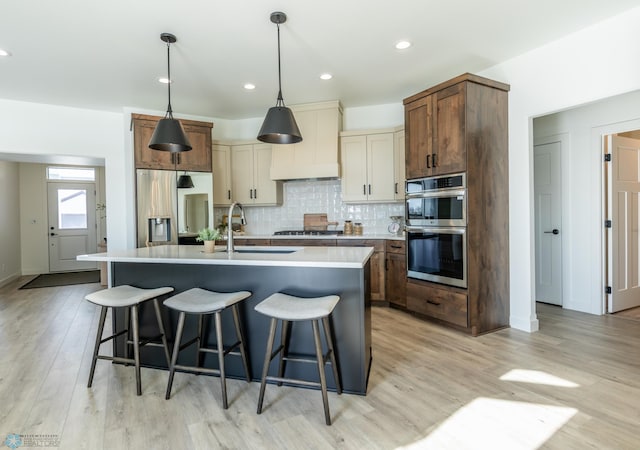 kitchen with appliances with stainless steel finishes, a breakfast bar, a sink, and backsplash