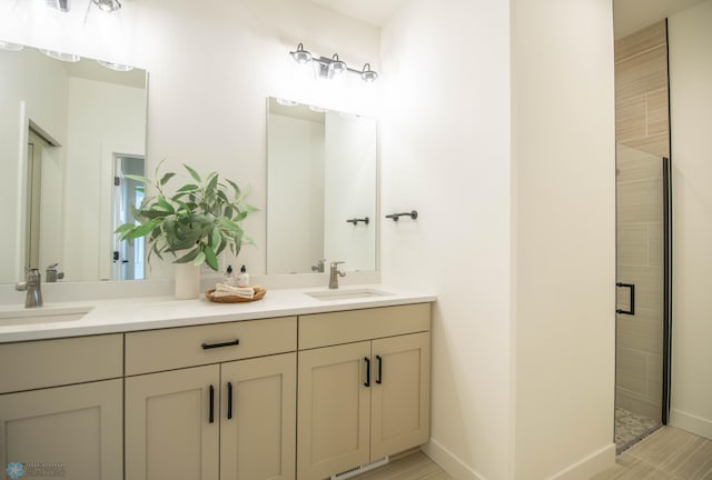 bathroom with double vanity, a stall shower, a sink, and baseboards