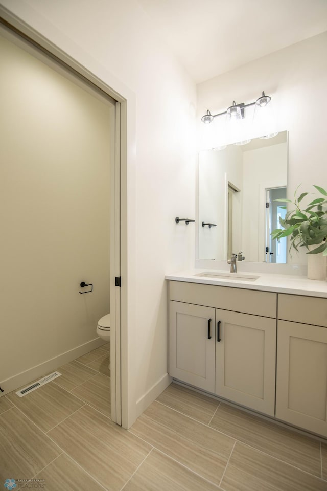 bathroom featuring baseboards, visible vents, vanity, and toilet