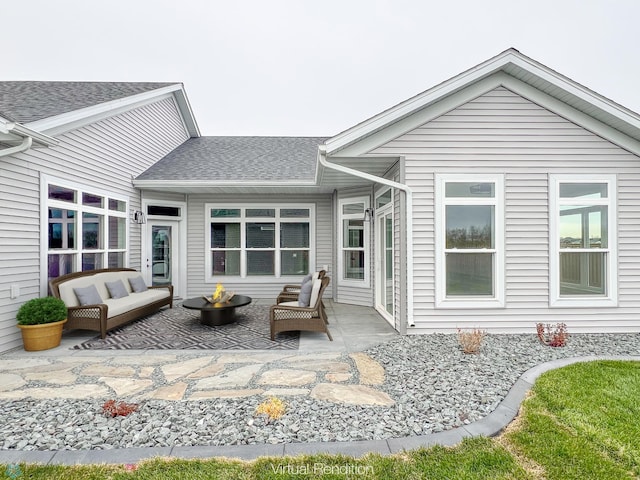 rear view of house with a patio area, a shingled roof, and an outdoor living space with a fire pit