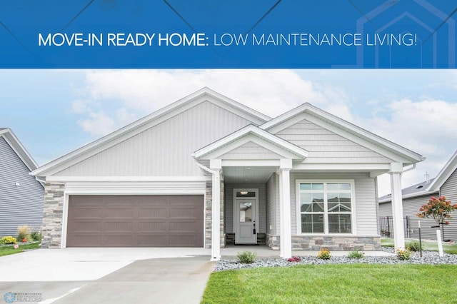 view of front of property featuring a garage, stone siding, a front yard, and driveway