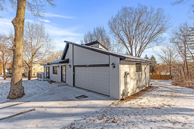 view of snow covered exterior with a garage