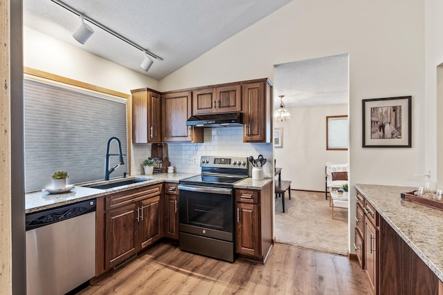 kitchen featuring lofted ceiling, sink, light stone countertops, and appliances with stainless steel finishes