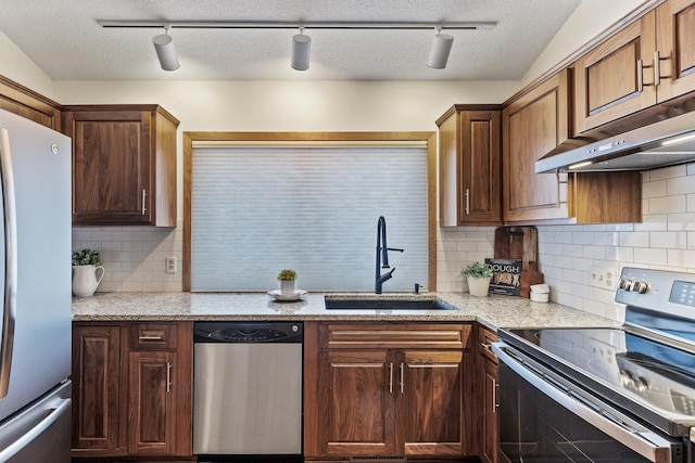 kitchen featuring tasteful backsplash, sink, stainless steel appliances, light stone countertops, and a textured ceiling