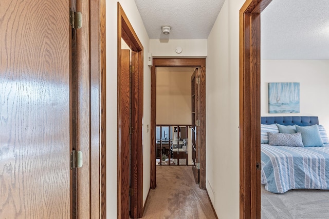 hallway featuring light colored carpet and a textured ceiling