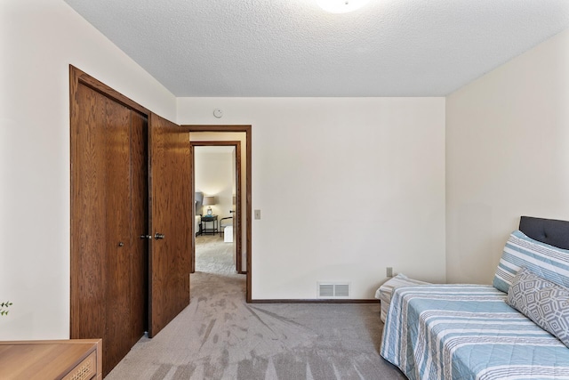 carpeted bedroom with a closet and a textured ceiling