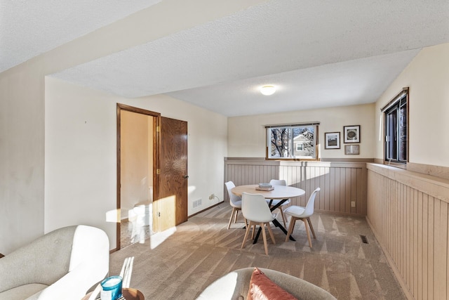 carpeted dining space featuring a textured ceiling