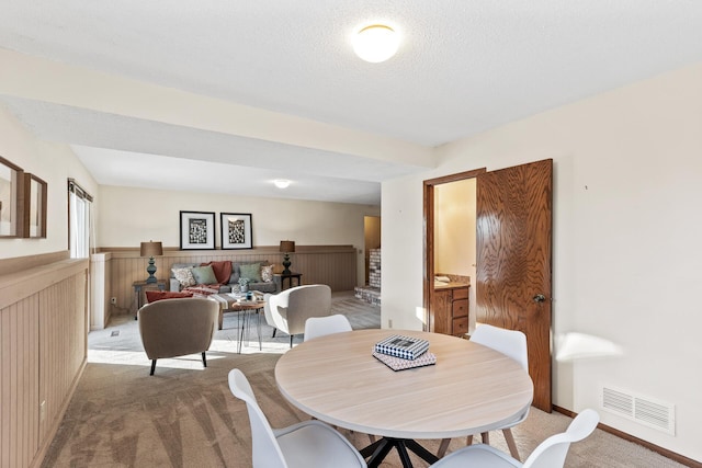 carpeted dining area with a textured ceiling