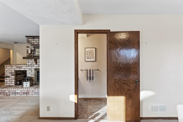 corridor with a textured ceiling and carpet flooring