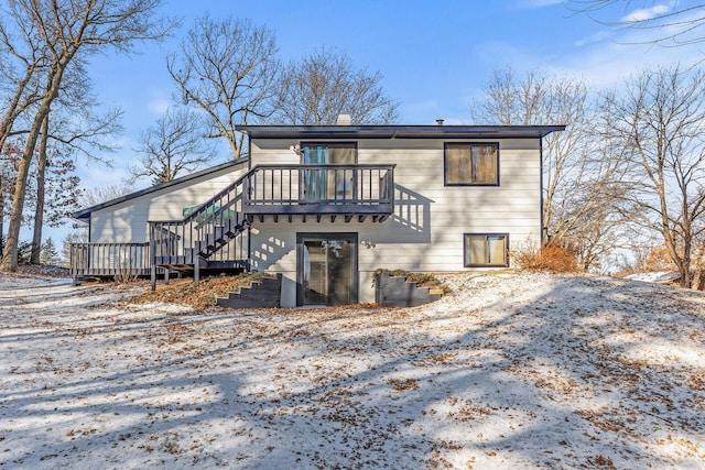 snow covered back of property featuring a deck