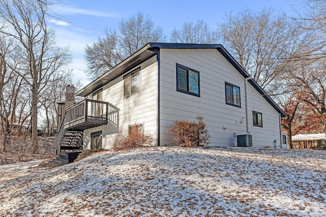 snow covered property with a wooden deck and central air condition unit