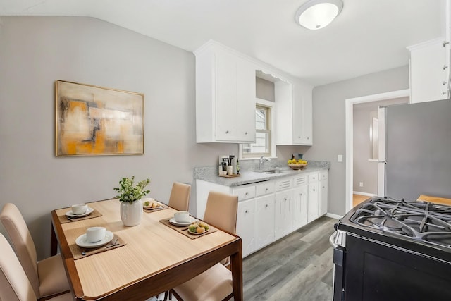 kitchen with range with gas stovetop, white cabinetry, lofted ceiling, stainless steel fridge, and light hardwood / wood-style flooring