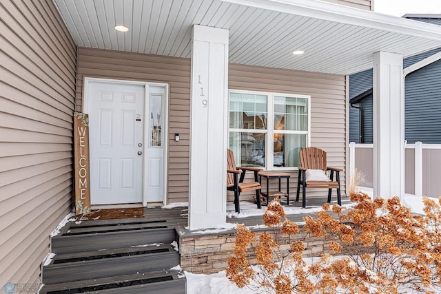 snow covered property entrance with a porch