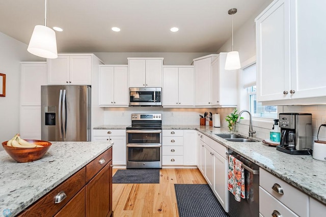 kitchen featuring white cabinets, appliances with stainless steel finishes, and pendant lighting