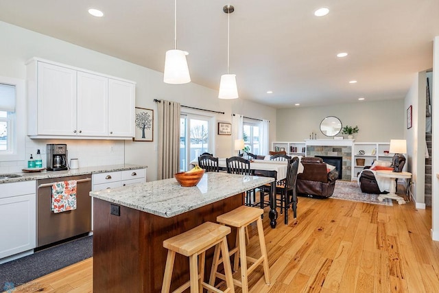 kitchen with white cabinetry, pendant lighting, stainless steel dishwasher, and a fireplace