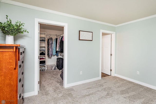 unfurnished bedroom with a closet, a walk in closet, crown molding, and light colored carpet