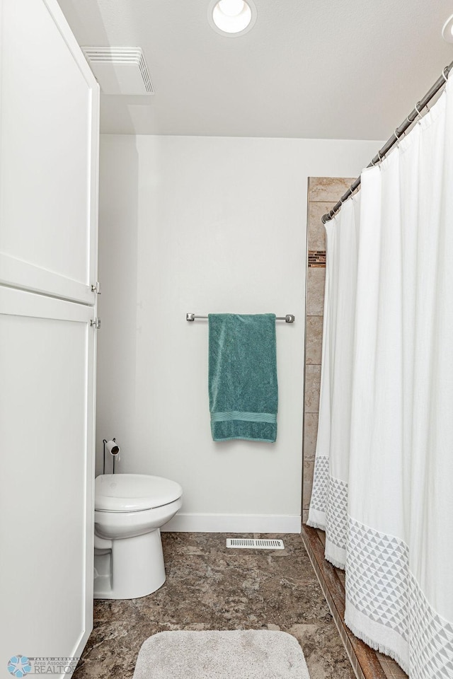 bathroom with curtained shower and toilet