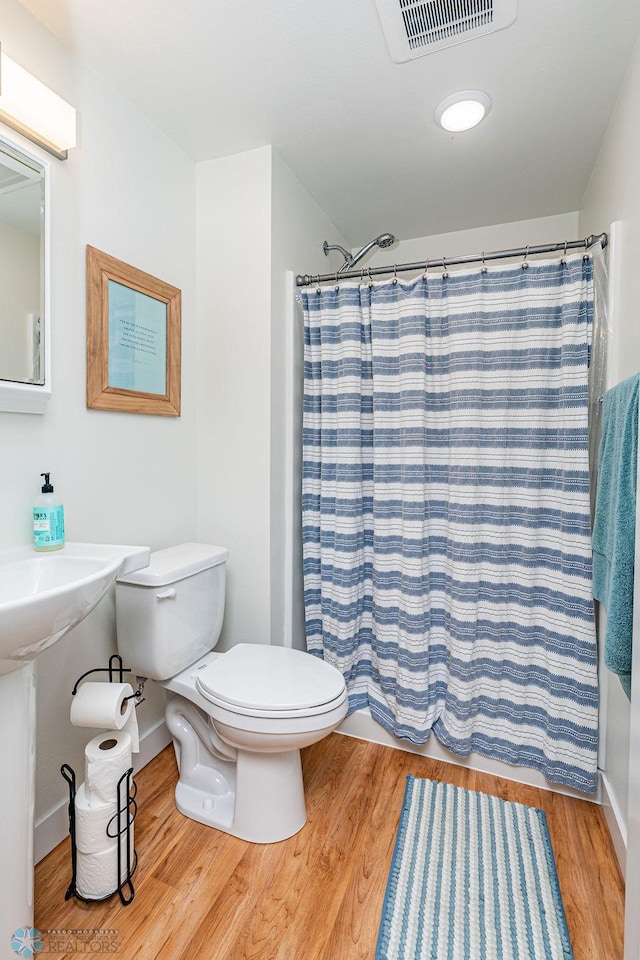 bathroom featuring toilet, a shower with shower curtain, and hardwood / wood-style floors