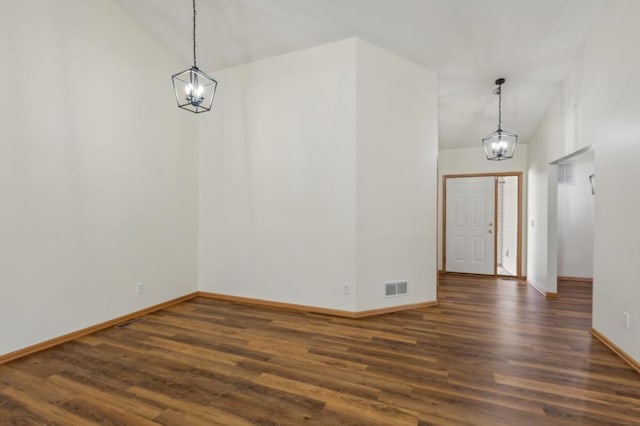 interior space featuring dark wood-type flooring, a notable chandelier, and vaulted ceiling