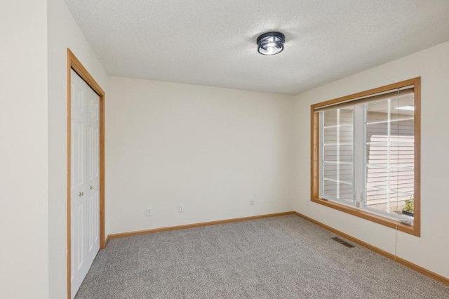 unfurnished bedroom featuring a closet, a textured ceiling, and carpet flooring