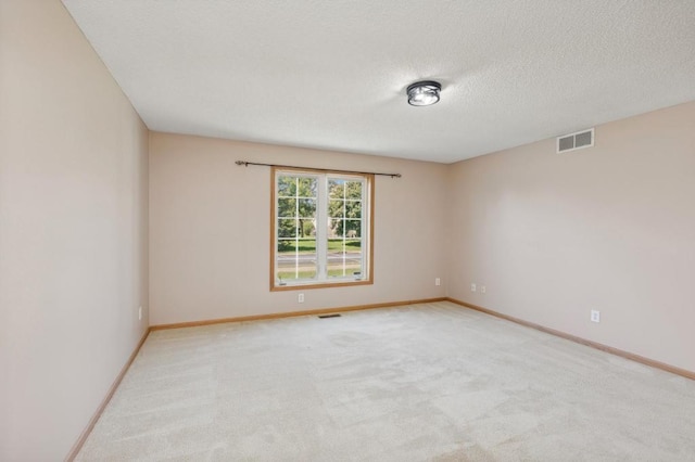 empty room featuring light colored carpet and a textured ceiling